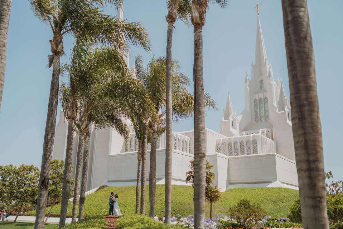 Couple on their wedding day facing each other in front of the LDS temple in San Diego, California